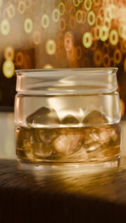 Golden Whiskey Glass with Ice Cubes Bokeh Background Wallpaper