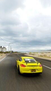 Stunning Yellow Porsche Cayman GT4 Driving on Coastal Road Wallpaper