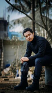 Young Man in Black Turtleneck Sitting Outdoors Portrait Wallpaper