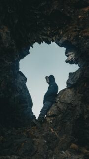 Adventurer Standing in Dramatic Rocky Cave Silhouette Mobile Wallpaper