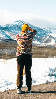 Adventurous Photographer in Snowy Mountain Landscape Phone Wallpaper