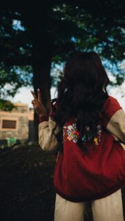 Woman Wearing Cartoon Jacket Making Peace Sign Mobile Wallpaper