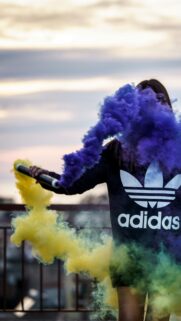 Girl Holding Vibrant Yellow and Purple Smoke Grenade Phone Wallpaper