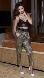 Stunning Selena Gomez in Sparkling Gold Pants and Leather Top Wallpaper