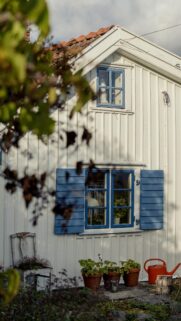 Cozy White Wooden Cottage with Blue Shutters Mobile Wallpaper