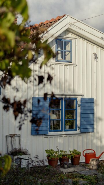 Cozy White Wooden Cottage with Blue Shutters Mobile Wallpaper