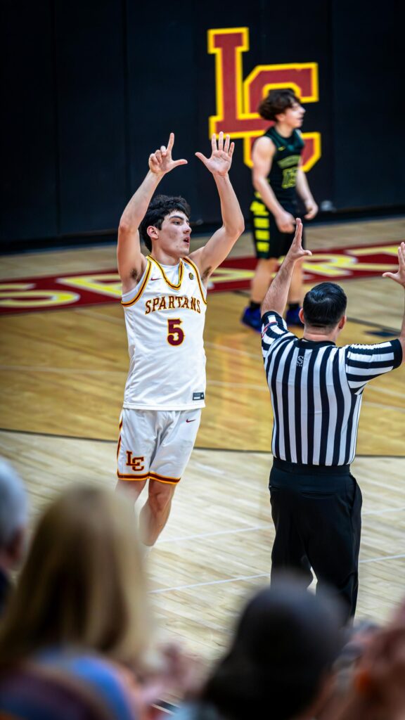 Exciting Basketball Player Celebrating Three Pointer Mobile Wallpaper