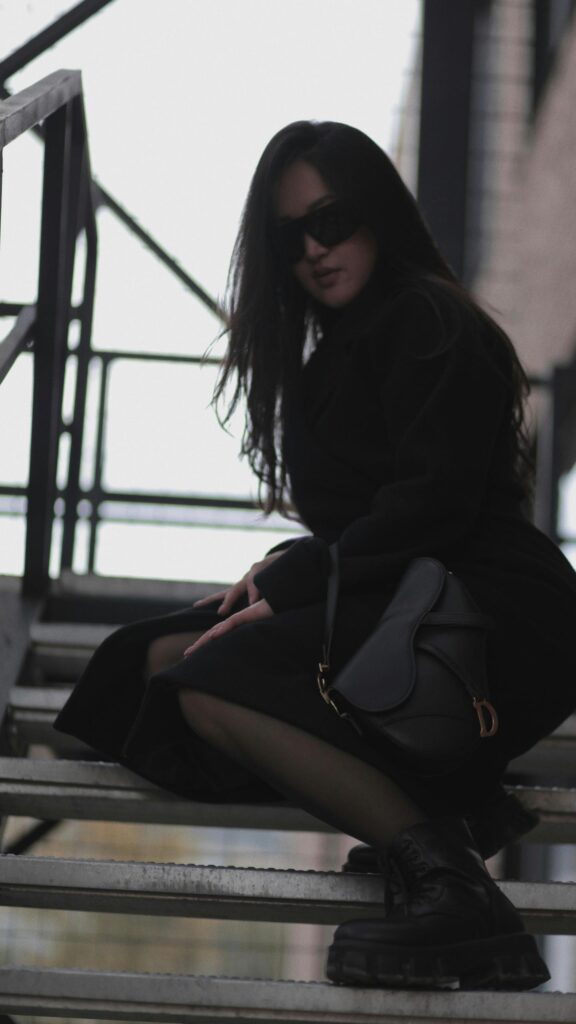 Stylish Woman in Black Coat with Designer Handbag Mobile Wallpaper