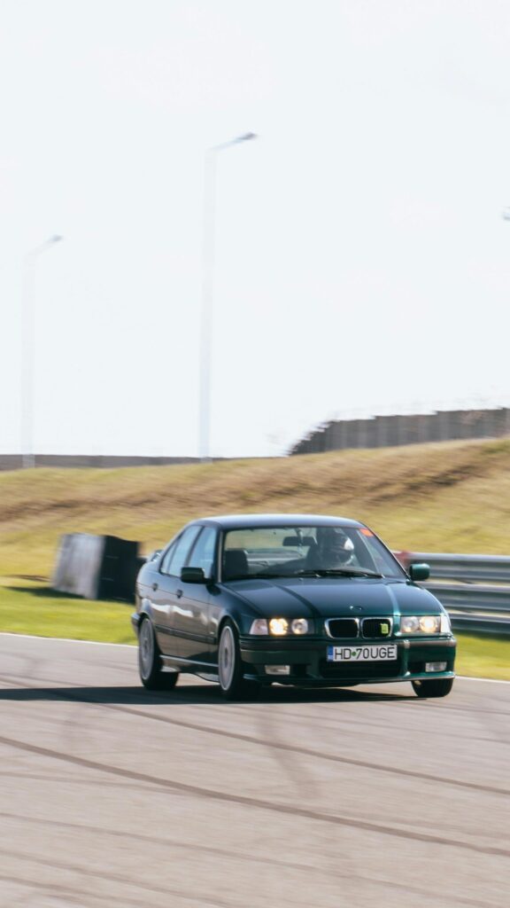 Dark Green BMW E36 Racing Sedan on Racetrack Mobile Wallpaper