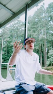Young Man Gesturing on Dock by the Lake Mobile Wallpaper