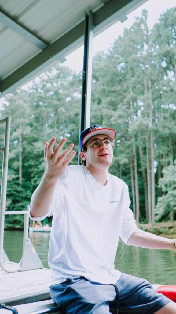 Young Man Gesturing on Dock by the Lake Mobile Wallpaper
