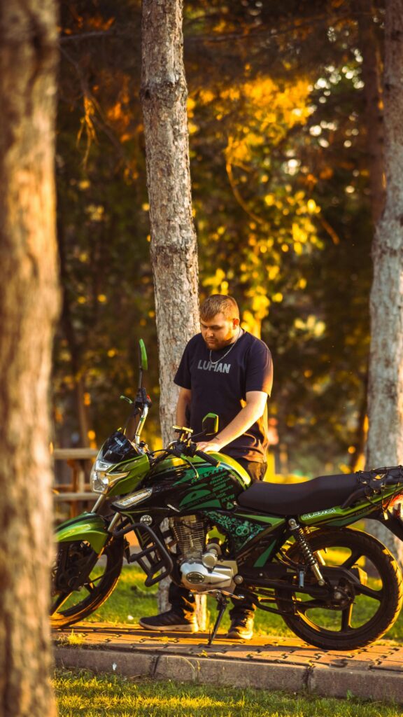 Young Man with Custom Green Motorcycle at Sunset Phone Wallpaper