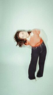 Retro Style Portrait of a Young Woman in an Orange Top Mobile Wallpaper