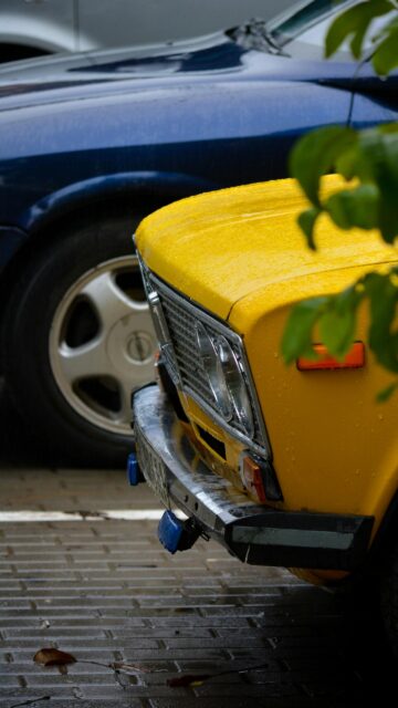 Vintage Yellow Soviet Car on Rainy Street Mobile Wallpaper