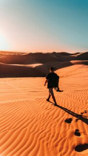 Solo Traveler Exploring Golden Desert Dunes Sunset Mobile Wallpaper