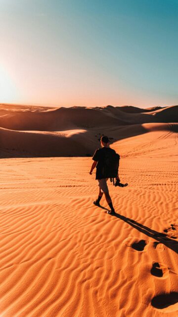 Solo Traveler Exploring Golden Desert Dunes Sunset Mobile Wallpaper