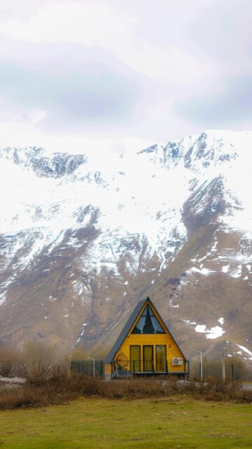 A-Frame Wooden Cabin Under Snowy Mountains Mobile Wallpaper