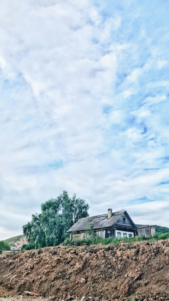Rustic Wooden Cottage Under a Cloudy Summer Sky Mobile Wallpaper