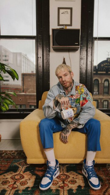 Stylish Man with Tattoos in Patchwork Denim Jacket Phone Wallpaper