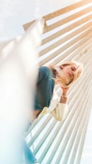 Blonde Woman in Layered Knitwear Under Architectural Structures Wallpaper