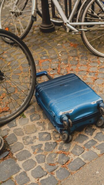 Travel Adventure Blue Luggage on Cobblestone Street Phone Wallpaper