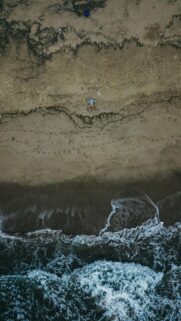 Aerial View of a Person Running on a Sandy Beach Ocean Wallpaper