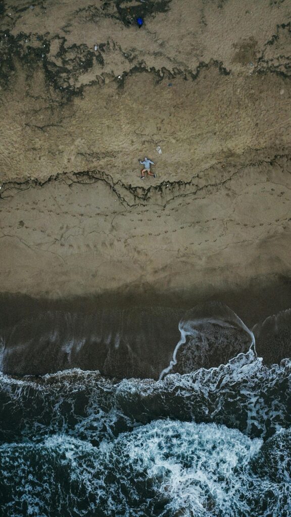 Aerial View of a Person Running on a Sandy Beach Ocean Wallpaper