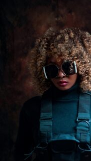 Stylish Woman with Curly Blonde Hair and Sunglasses Phone Wallpaper