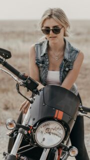 Stylish Biker Girl with Denim Vest on Motorcycle Phone Wallpaper