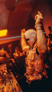 DJ in Futuristic Tactical Mask and Vest at EDM Party Wallpaper