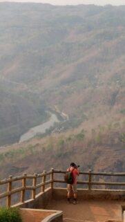 Photographer Exploring Hazy River Valley Scenic View Mobile Wallpaper