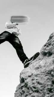 Aesthetic Low Angle View Man Standing on Rock Peak Phone Wallpaper