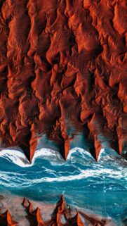Aerial View of Red Desert Dunes Meeting Blue Ocean Waves Wallpaper
