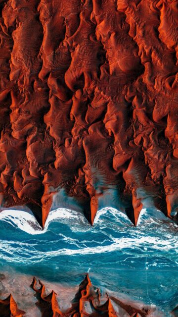 Aerial View of Red Desert Dunes Meeting Blue Ocean Waves Wallpaper