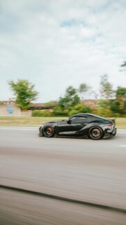 Black Toyota Supra Sports Car Driving on Highway Mobile Wallpaper