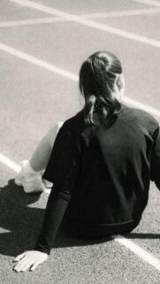 Young Female Athlete Resting on Running Track Minimalist Phone Wallpaper