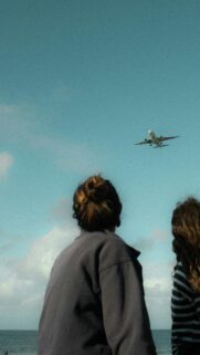 Awe-Inspiring Airplane Flight Over Beach View Mobile Wallpaper