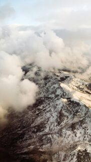 Aerial View of Snowy Mountain Peak with Clouds Wallpaper