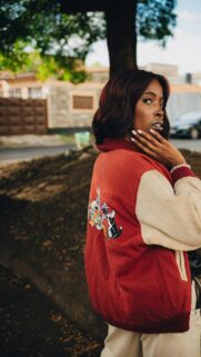 Stylish Woman Wearing Looney Tunes Varsity Jacket Mobile Wallpaper