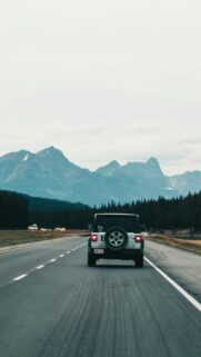 White Jeep Wrangler Driving Towards Majestic Mountains Mobile Wallpaper