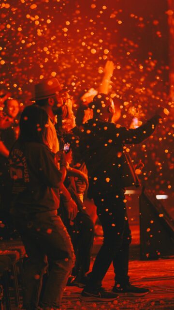 People Dancing at Night Concert with Glowing Confetti Effects Wallpaper