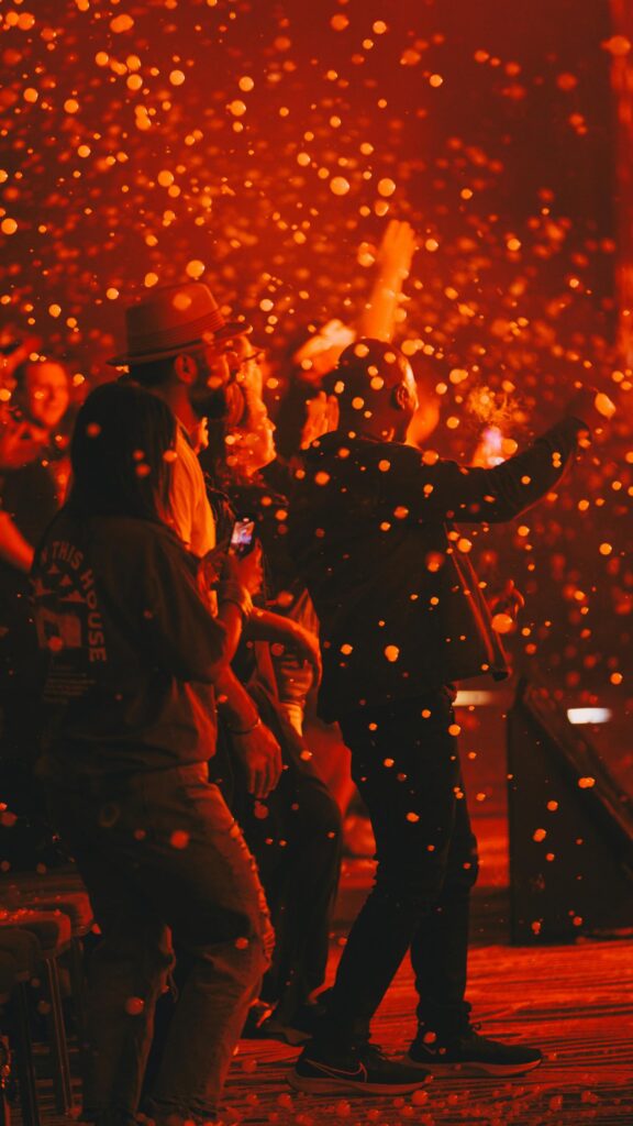 People Dancing at Night Concert with Glowing Confetti Effects Wallpaper