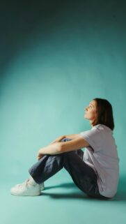 Minimalist Portrait of Woman Looking Up on Teal Background Mobile Wallpaper