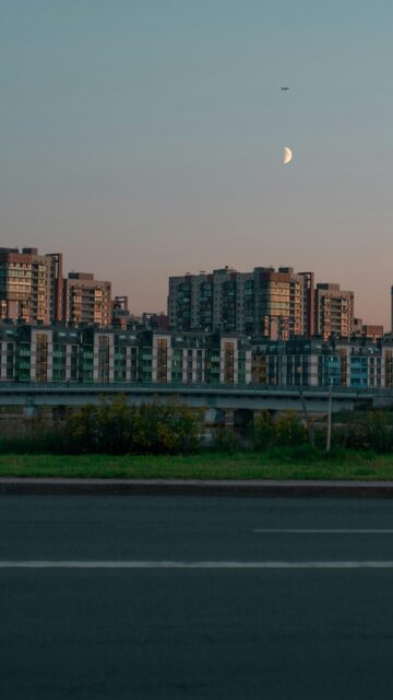 Stunning Urban Skyline with Moon and Airplane Mobile Wallpaper