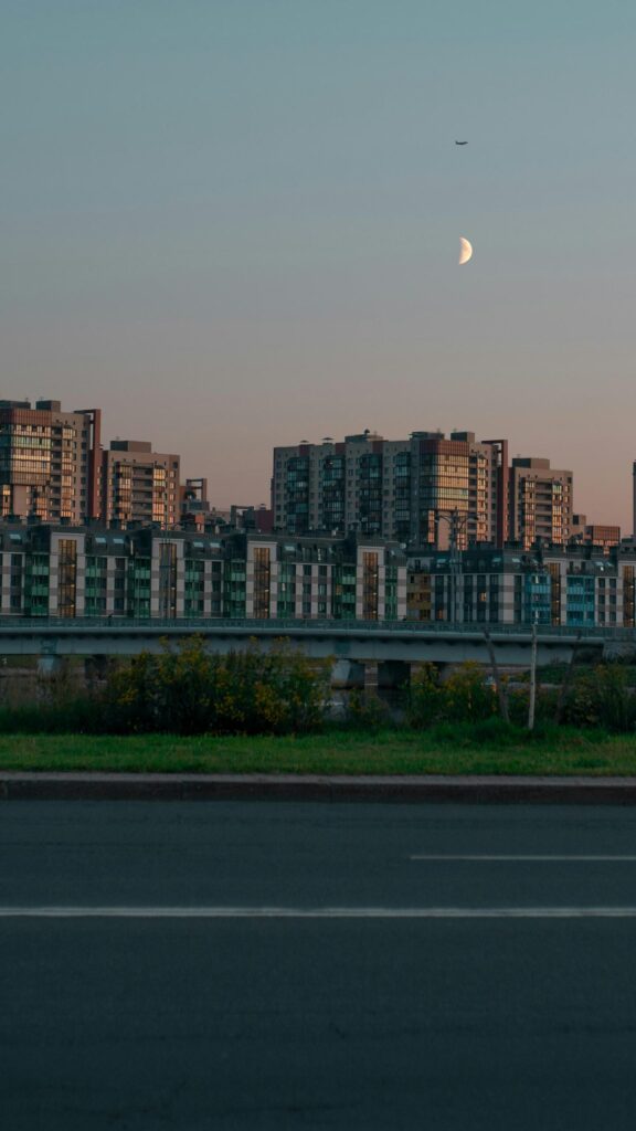 Stunning Urban Skyline with Moon and Airplane Mobile Wallpaper