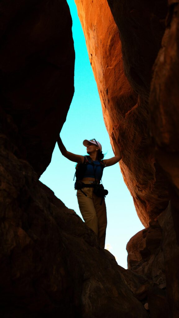 Woman Adventurer Exploring Narrow Red Rock Slot Canyon Wallpaper