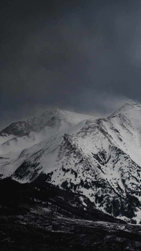 Dramatic Snowy Mountain Peak in Dark Winter Clouds Phone Wallpaper