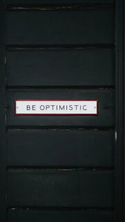 Be Optimistic Sign on Dark Paneled Wall Mobile Wallpaper