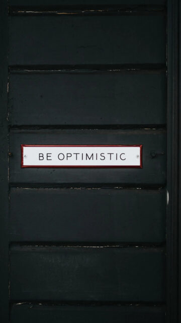 Be Optimistic Sign on Dark Paneled Wall Mobile Wallpaper