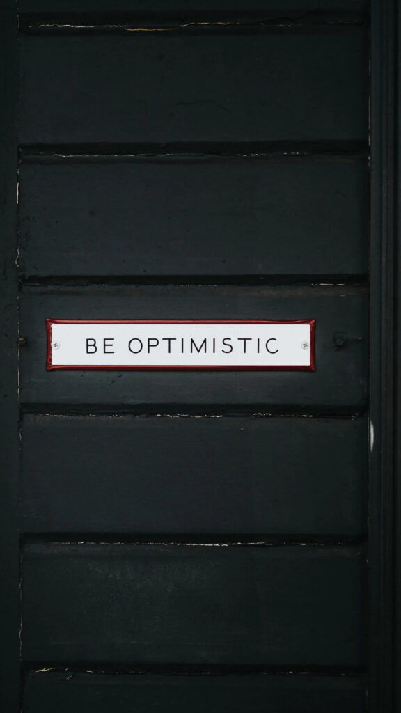 Be Optimistic Sign on Dark Paneled Wall Mobile Wallpaper